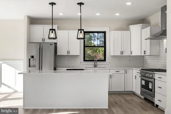 a large kitchen with kitchen island white cabinets and stainless steel appliances