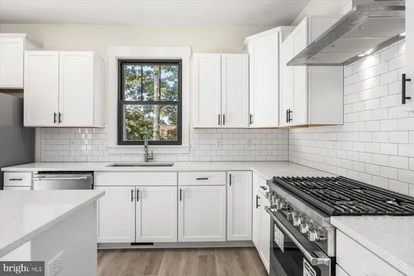a kitchen with white cabinets appliances a sink and a window