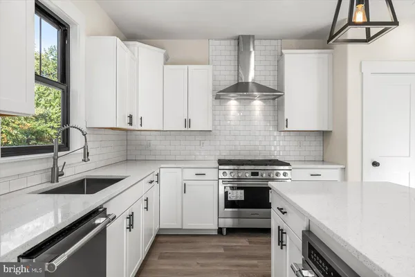 a kitchen with stainless steel appliances white cabinets and a stove top oven