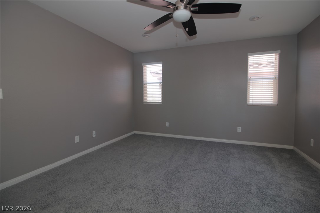 9289 Valley Ranch Avenue Las Vegas, NV 89178 - Photo 20 of 29 A well-lit bedroom features plush carpeting and a ceiling fan for comfort.