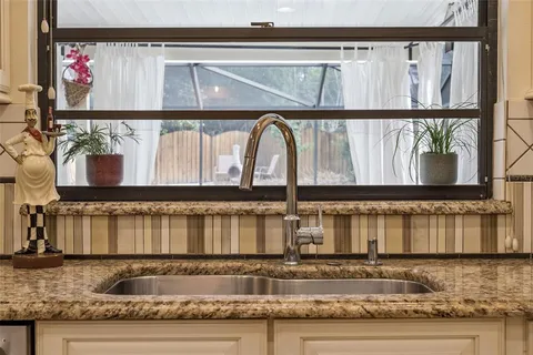 a kitchen with white cabinets and sink