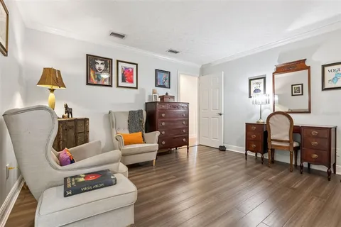 a spacious bedroom with a bed a dresser and potted plant on the dresser