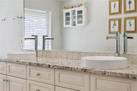 a bathroom with a granite countertop double vanity sink and mirror