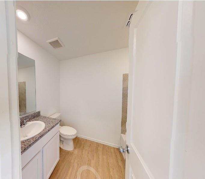 9757 Platteview Road Fort Worth, TX 76179 - Photo 15 of 19 Bathroom featuring a white vanity with a granite-look countertop, an undermount sink, and wood-finish flooring