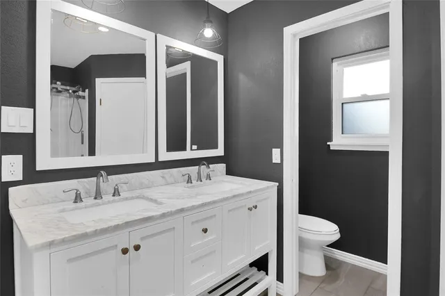 a bathroom with a granite countertop sink mirror and toilet