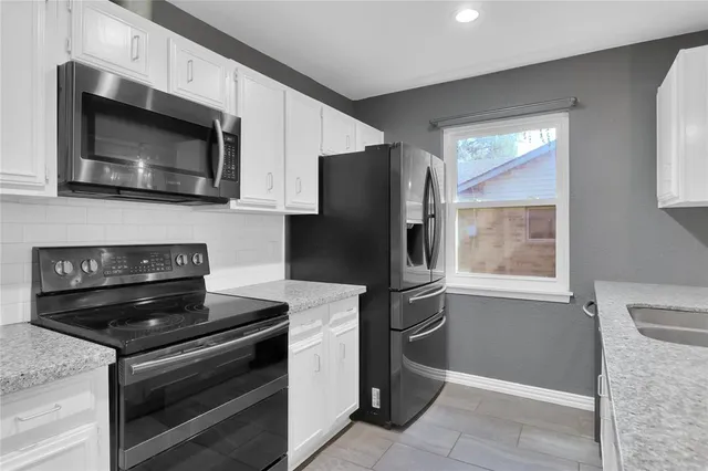 a kitchen with granite countertop white cabinets and stainless steel appliances