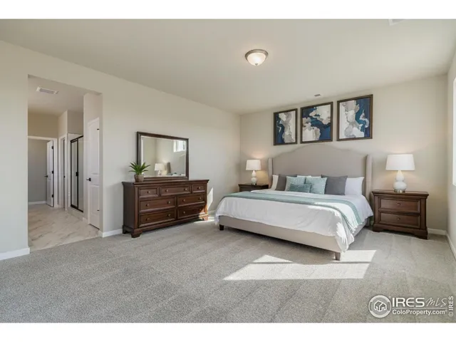 a spacious bedroom with a bed and a lamp