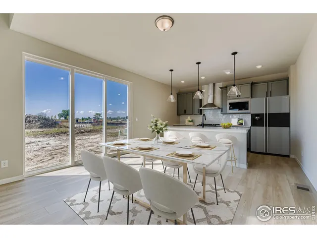 a kitchen with stainless steel appliances kitchen island granite countertop a dining table chairs and white cabinets