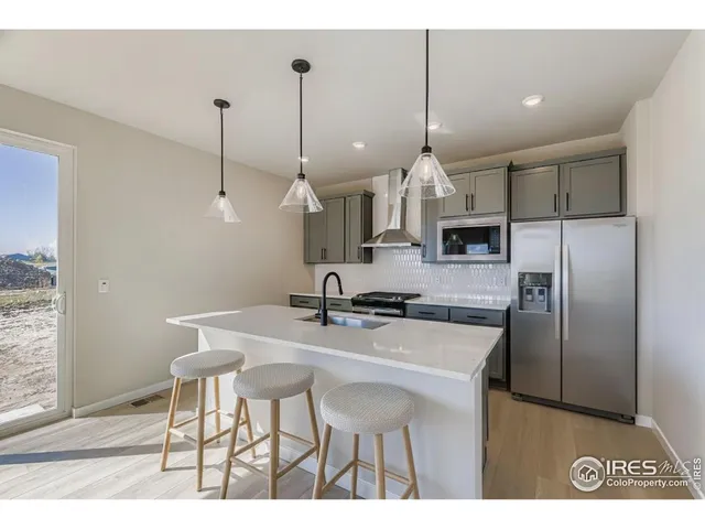 a kitchen with kitchen island a dining table chairs stainless steel appliances and cabinets