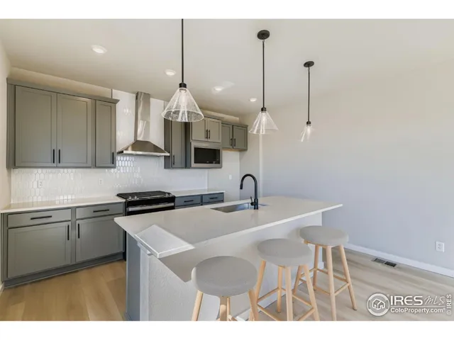 a kitchen with stainless steel appliances granite countertop a sink a stove a dining table and chairs