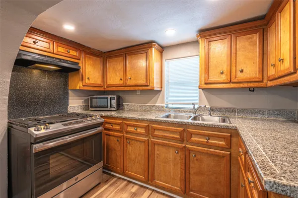 a kitchen with stainless steel appliances granite countertop a stove a sink and a microwave