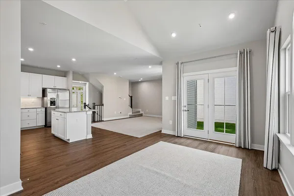 a large white kitchen with stainless steel appliances granite countertop a refrigerator a sink a stove and white cabinets with wooden floor
