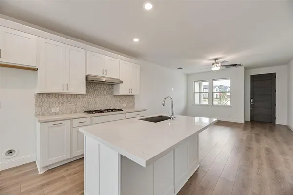 a kitchen that has a lot of white cabinets and wooden floor