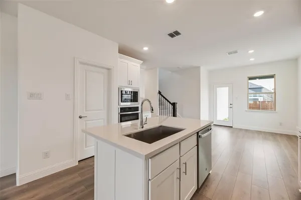 a kitchen that has a sink a stove and wooden floor