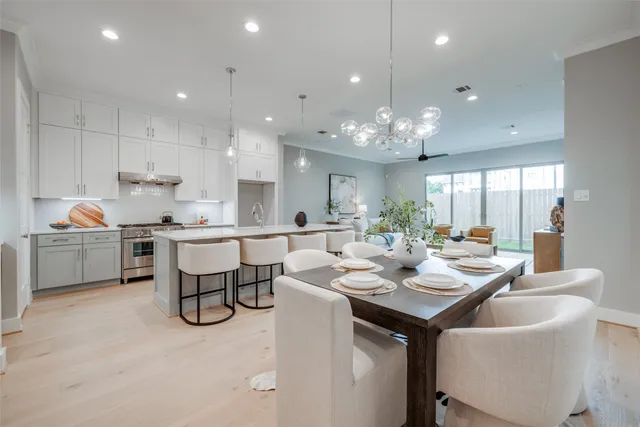 a kitchen with a dining table chairs cabinets wooden floor and appliances