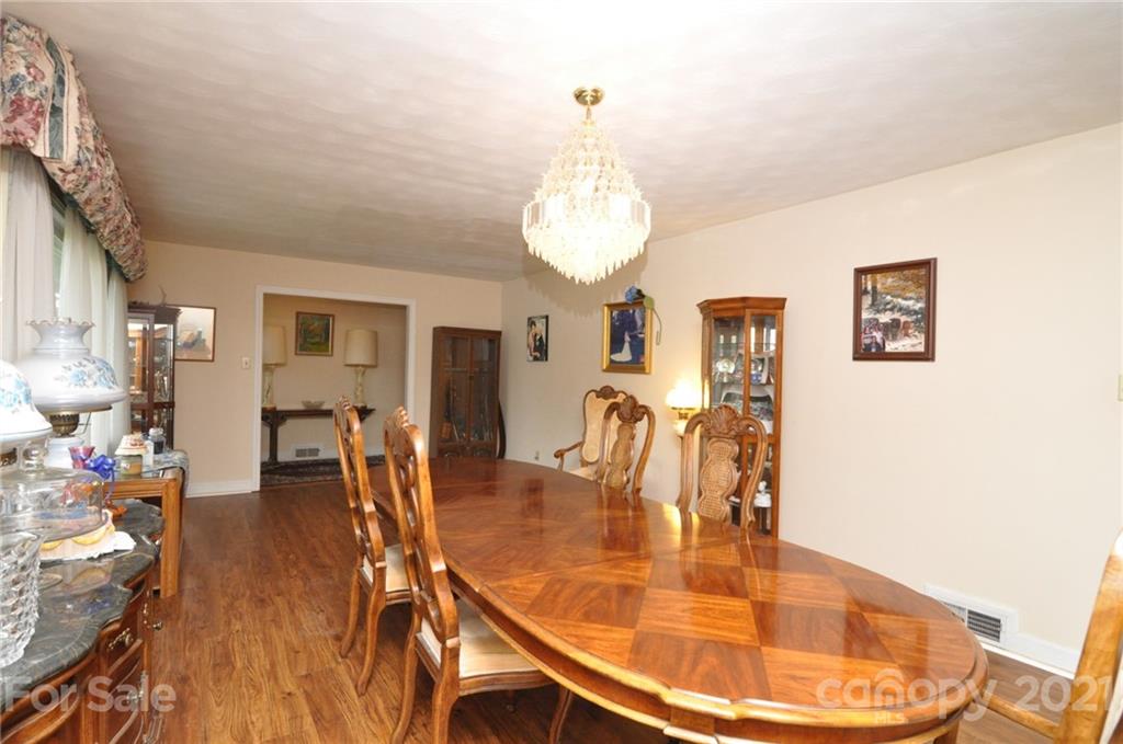 501 Redland Road Landrum, SC 29356 - Photo 12 of 38 a dining room with wooden floor a chandelier a wooden table and chairs