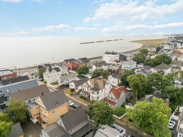 an aerial view of a city with lots of residential buildings ocean and mountain view in back