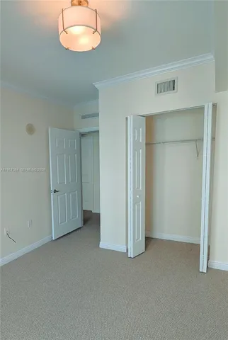 an empty room that has a chandelier fan and window