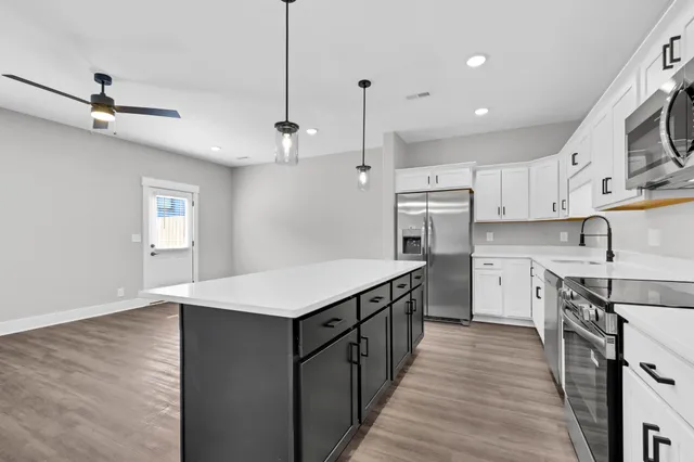 a kitchen with kitchen island a sink stainless steel appliances and cabinets