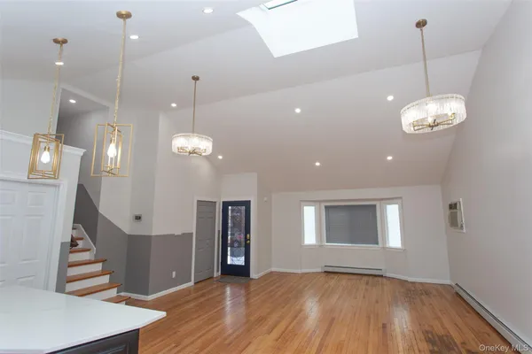 a view of an empty room with wooden floor and a chandelier
