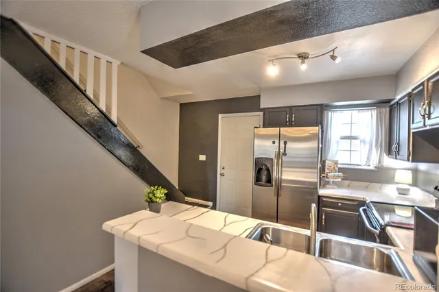 a kitchen with kitchen island a counter top space a sink stainless steel appliances and cabinets