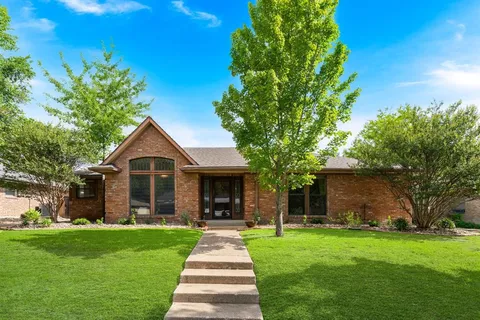 a front view of a house with a yard and garden