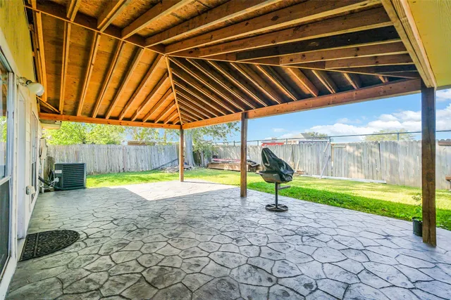 a view of swimming pool with lawn chairs and couches under an umbrella
