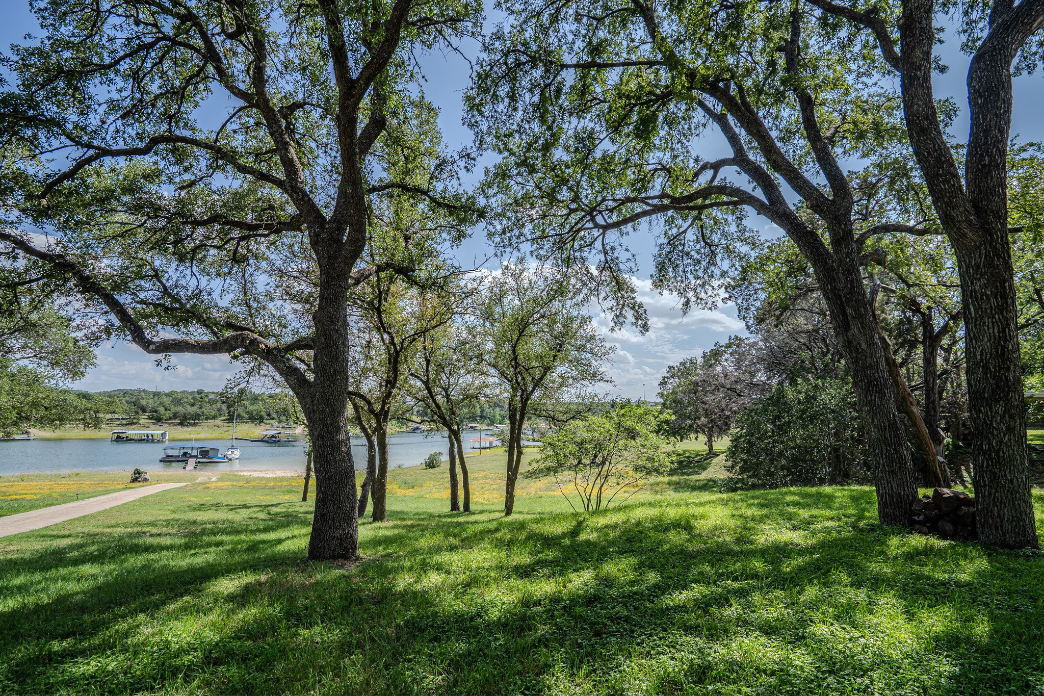 16013 Edwards Drive Austin, TX 78734 - Photo 3 of 18 A tranquil lakeside setting with mature trees overlooking still waters and distant boats.