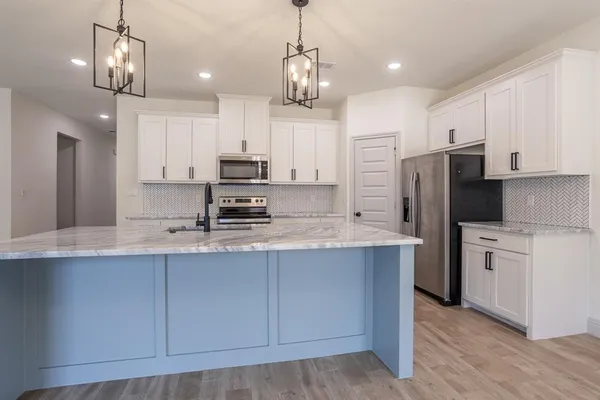 a large kitchen with kitchen island a stove a sink a refrigerator and a wooden floor
