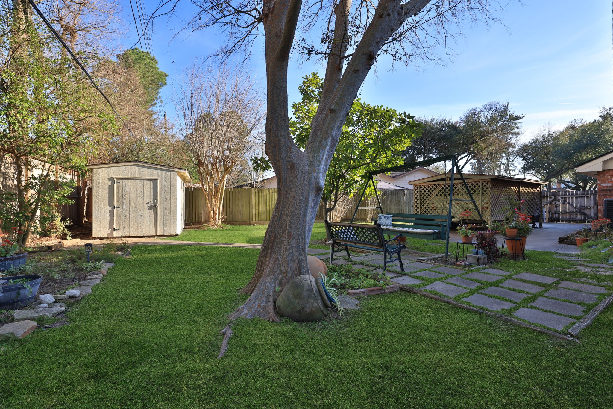 9102 Woodhouse Drive Spring, TX 77379 - Photo 26 of 32 BACK YARD - This view shows the storage shed on the left, a pretty sitting area with swing and park bench, and the side yard with a concrete pad for parking a camper or small boat. The double-gate opens wide to accommodate whatever you need. This large 10,912 s/f lot provides space for this extra amenity.