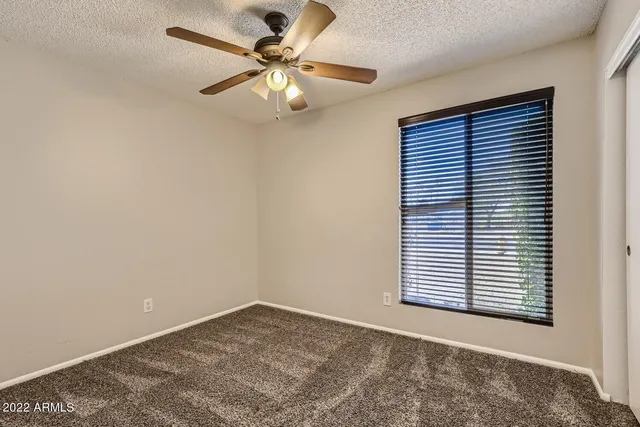 an empty room with windows and fan
