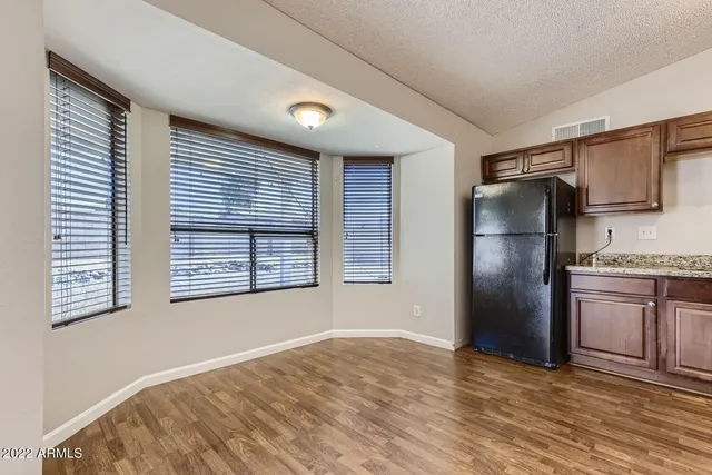 a view of an empty room with a kitchen and a window