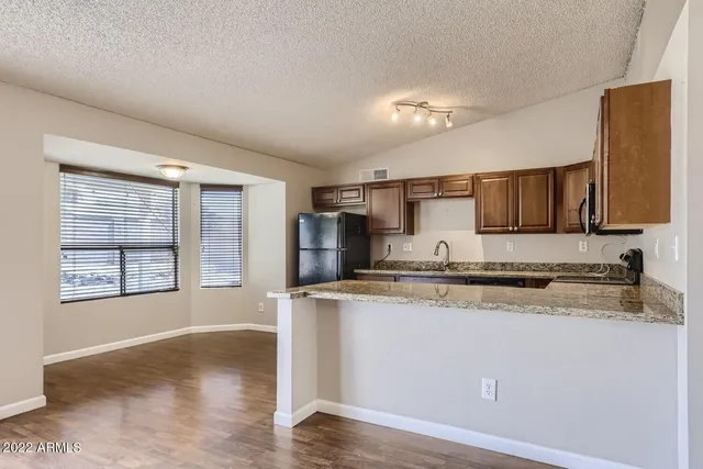 a kitchen with stainless steel appliances granite countertop a sink a stove a refrigerator a center island and cabinets