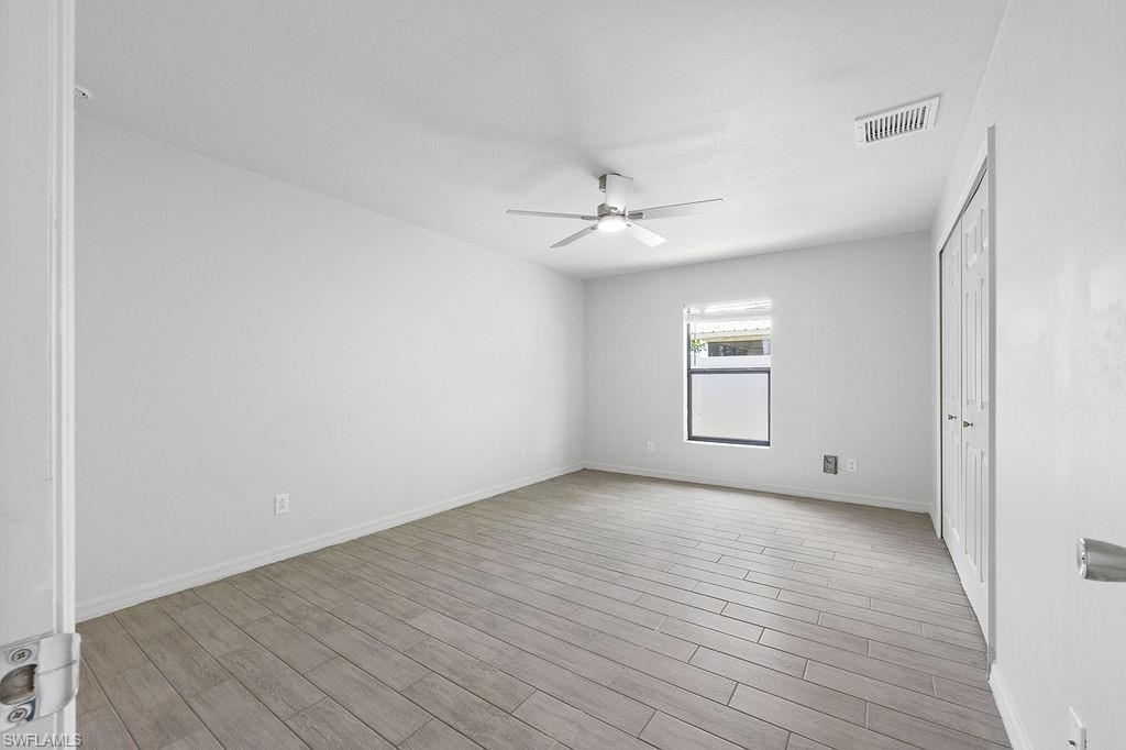 3429 Southwest 8th Place Cape Coral, FL 33914 - Photo 11 of 19 an empty room with wooden floor chandelier fan and windows