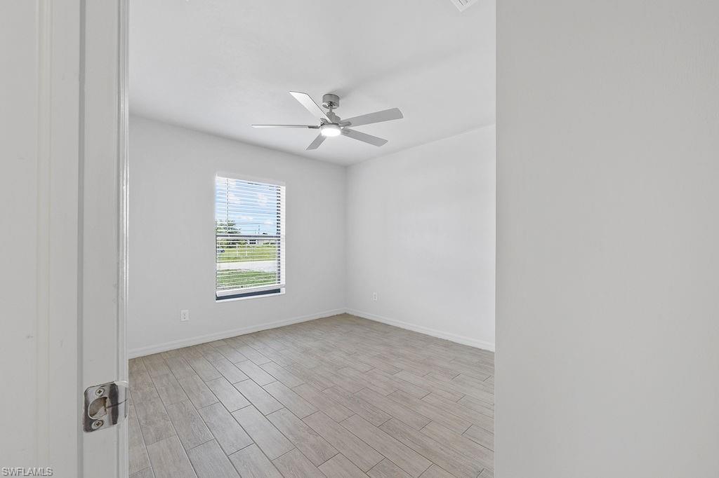 3429 Southwest 8th Place Cape Coral, FL 33914 - Photo 4 of 19 an empty room with wooden floor ceiling fan and windows