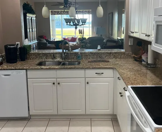 a kitchen with granite countertop a sink a stove and cabinets