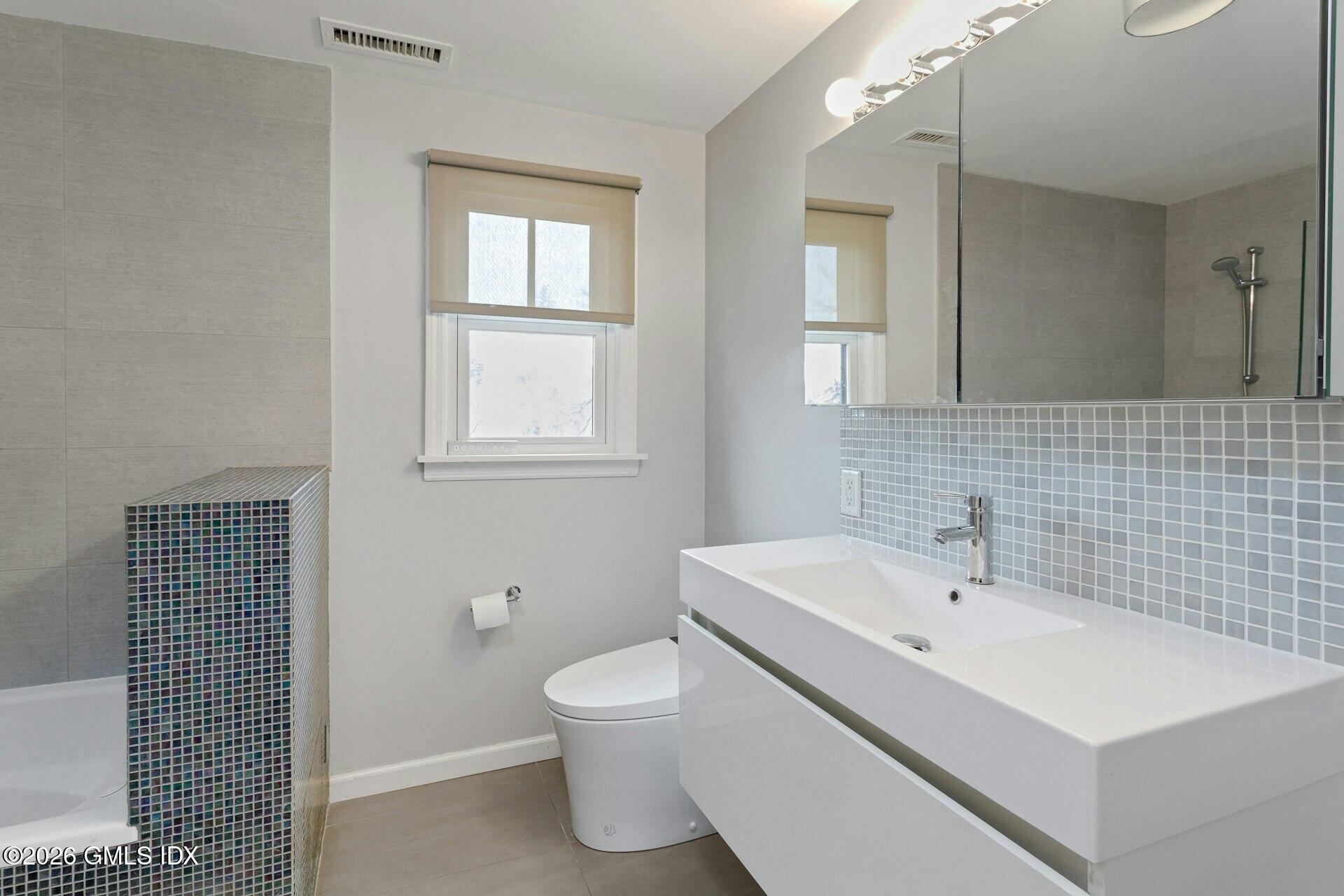 83 Burning Tree Road Greenwich, CT 06830 - Photo 16 of 26 a bathroom with a sink a toilet and mirror
