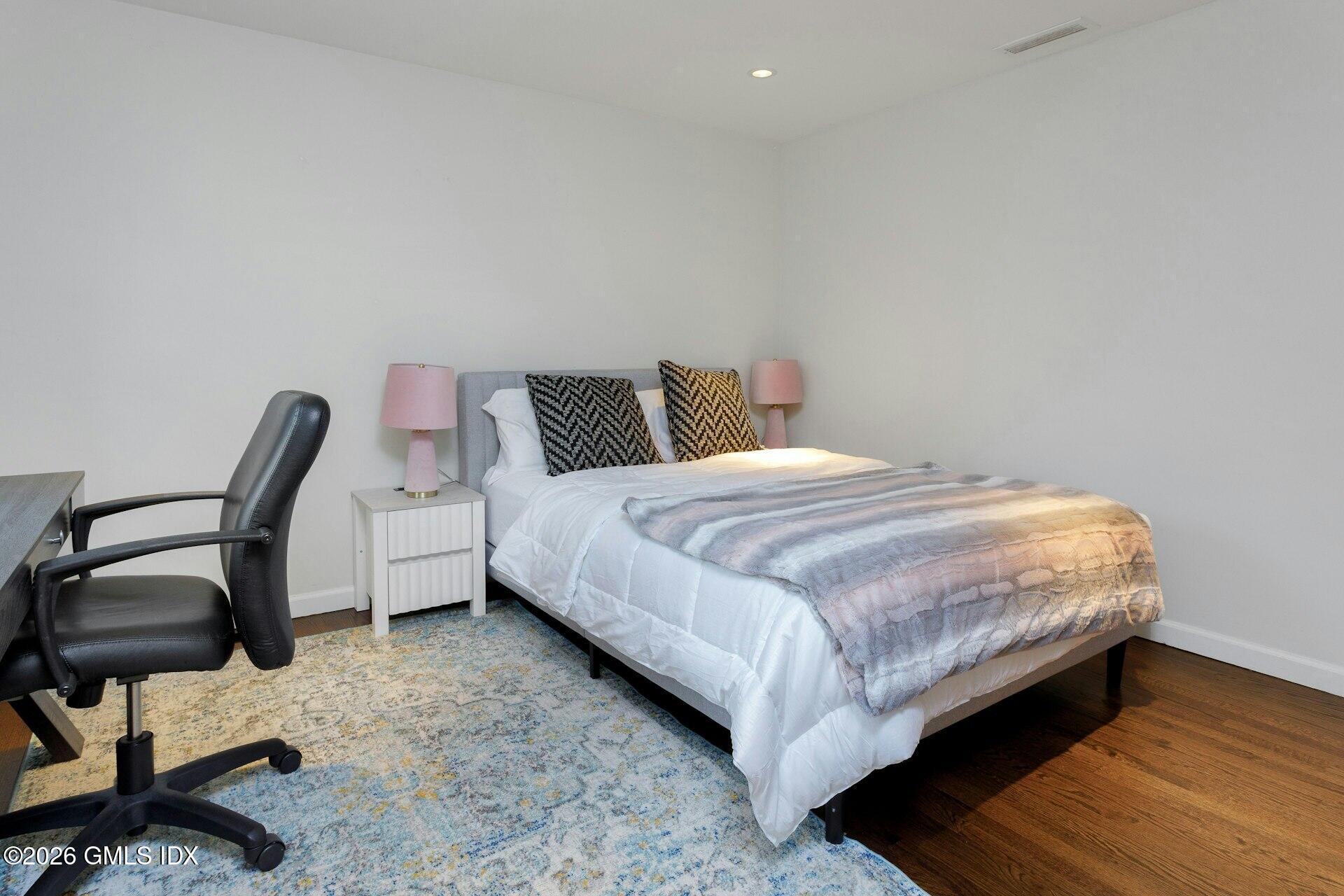 83 Burning Tree Road Greenwich, CT 06830 - Photo 17 of 26 a bedroom with a bed and a chair