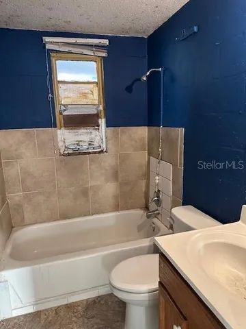 a bathroom with a granite countertop bathtub sink vanity mirror and toilet
