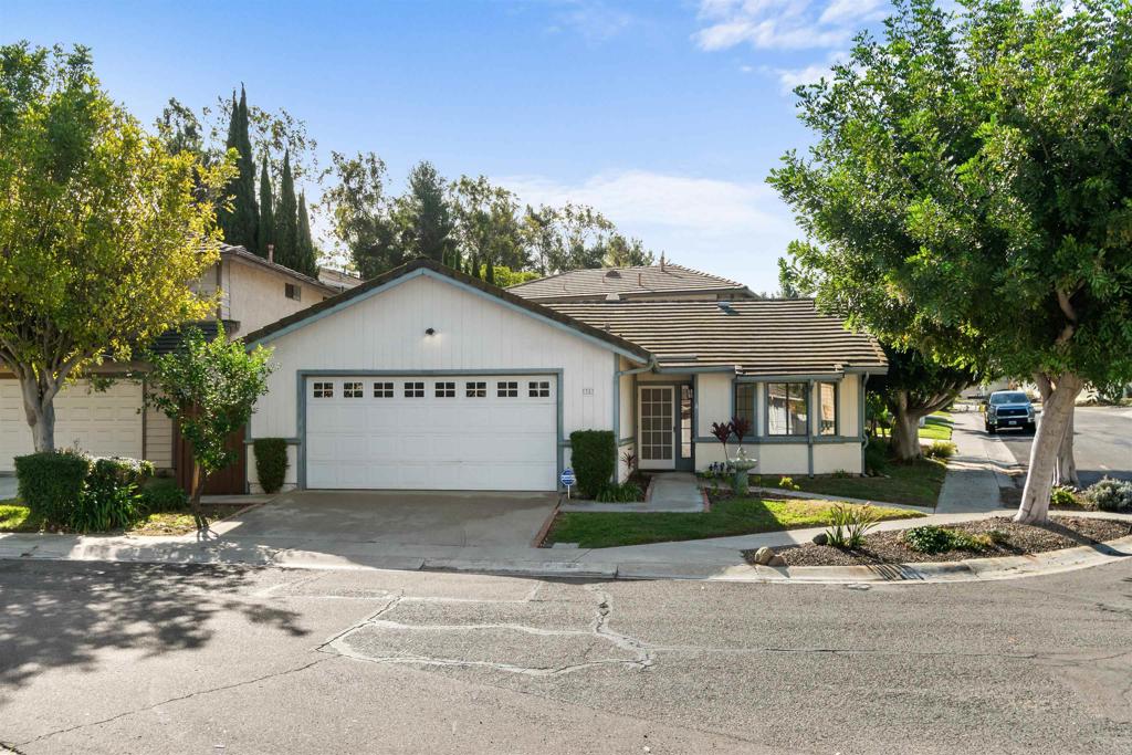 a view of a white house next to a yard and road