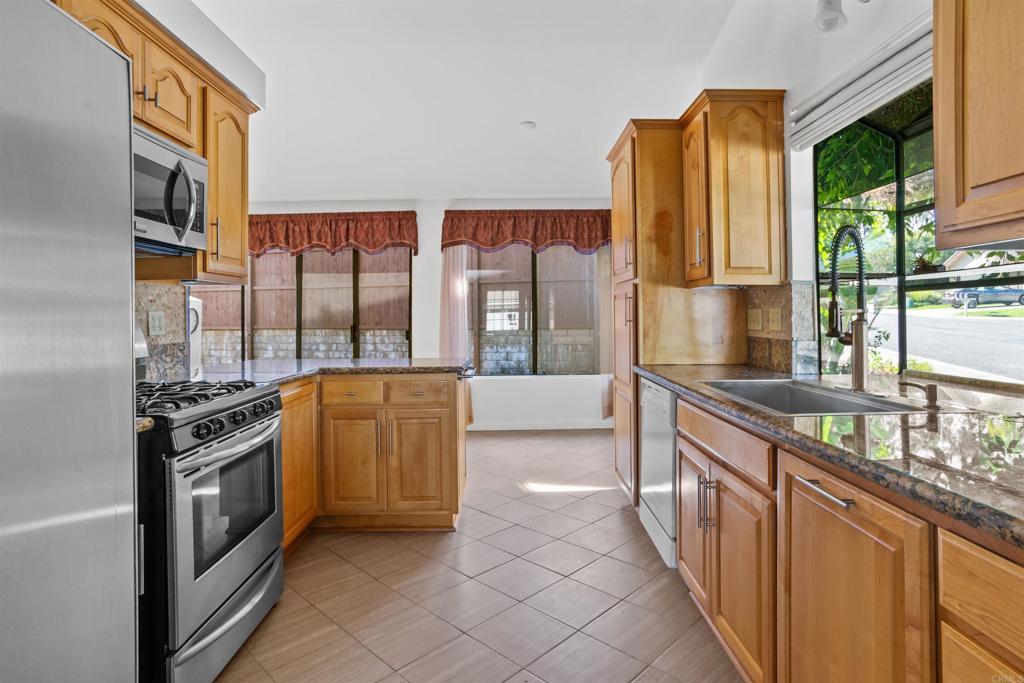 1387 Longfellow Road Vista, CA 92081 - Photo 15 of 38 a kitchen with stainless steel appliances granite countertop a stove a sink and a refrigerator