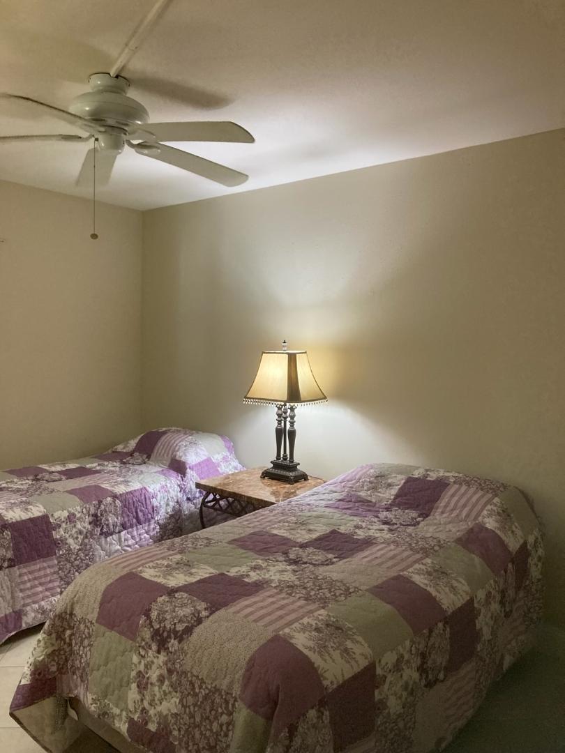 445 Saxony Way, Unit 445 Delray Beach, FL 33446 - Photo 7 of 10 a bedroom with a bed and a lamp
