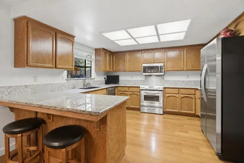 a kitchen with stainless steel appliances granite countertop a stove a sink and a refrigerator