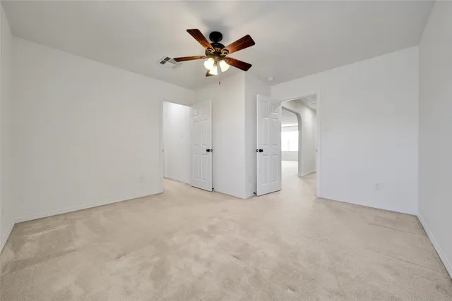 an empty room with closet and ceiling fan