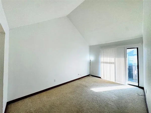a view of an empty room with wooden floor and windows