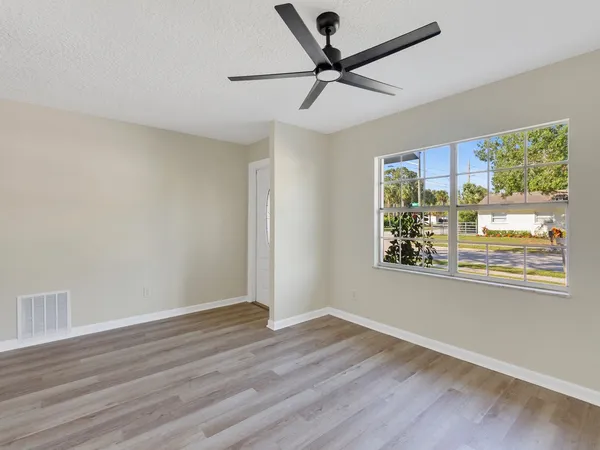 a view of empty room with wooden floor and fan