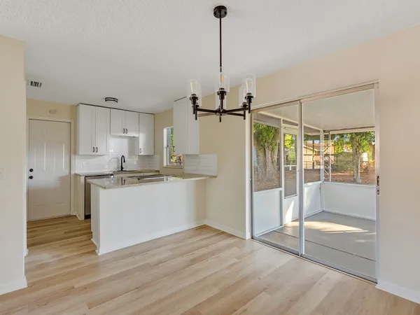 a room with kitchen island granite countertop wooden floor and a glass door shower