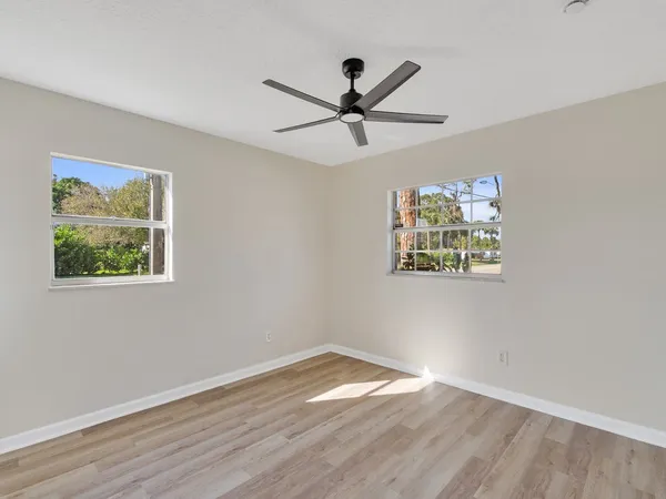 a view of empty room with wooden floor and fan