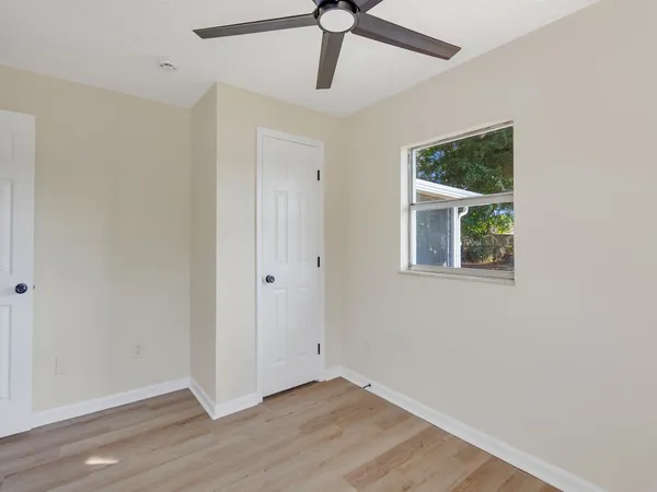 a view of an empty room with window and wooden floor