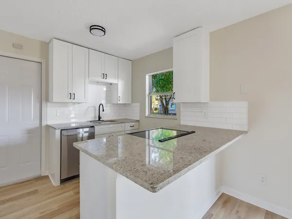 a kitchen with stainless steel appliances granite countertop a sink a stove and a refrigerator with wooden floor